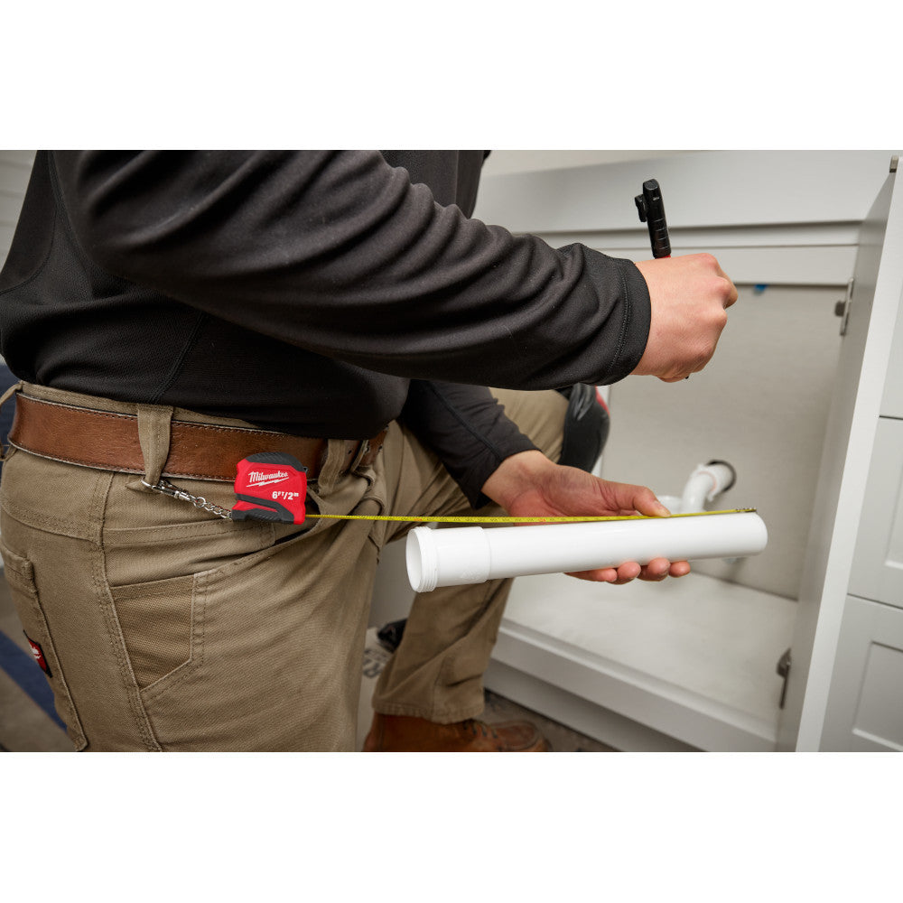 48-22-1706 6ft/2m Keychain Tape Measure showing in use measuring a piece of pipe while attached to a belt loop