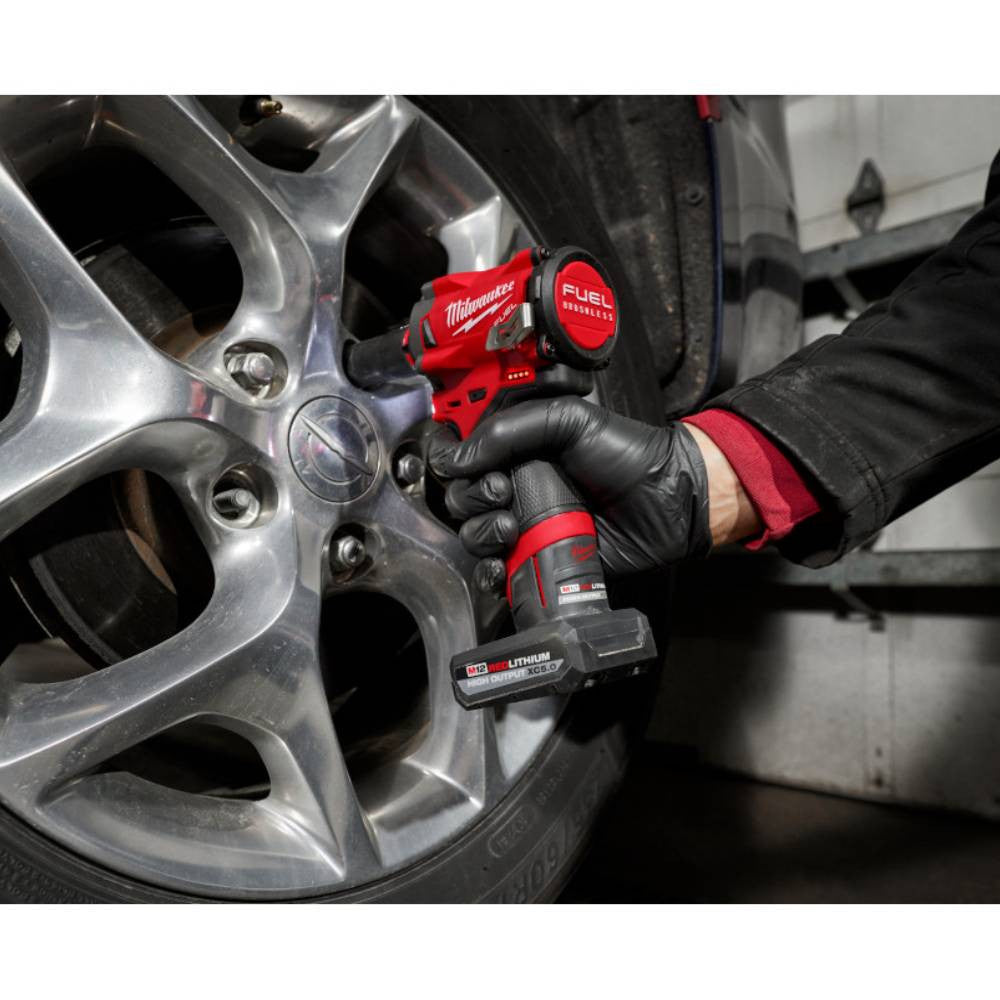Milwaukee 48-59-2450P M12 5.0 Ah Battery & Charger Starter Kit showing the battery in use powering a impact wrench to change a tire (Tool sold separately)