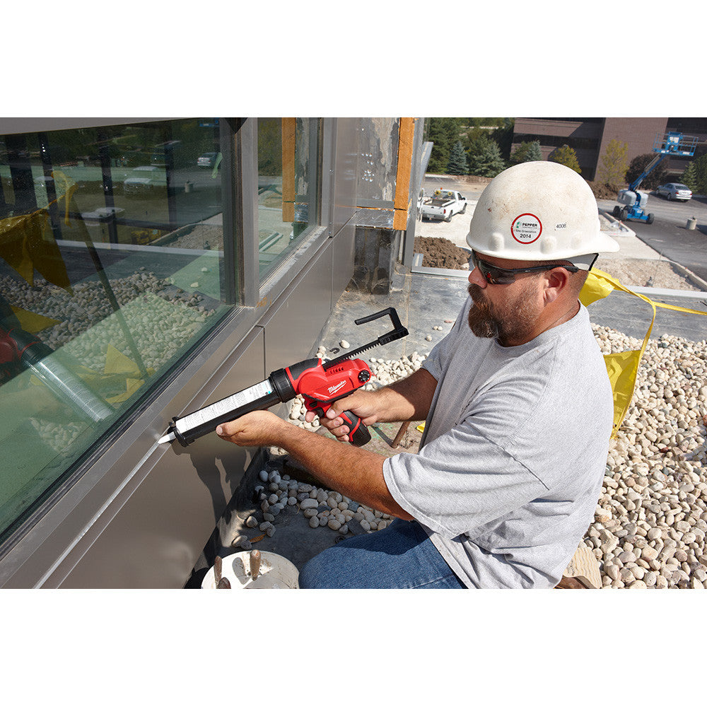 Milwaukee 2441-20 M12 Cordless 10oz. Caulk and Adhesive Gun (Tool Only) showing in use sealing windows on side of the wall