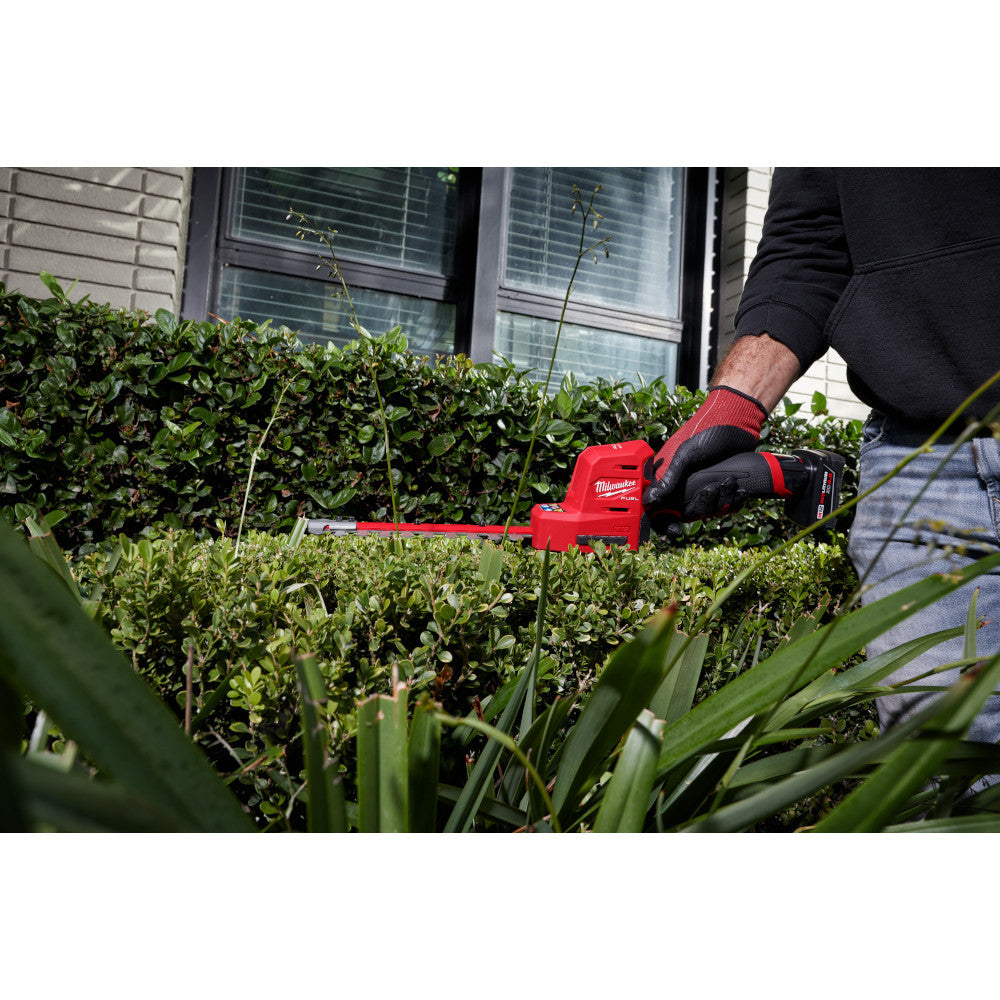 Milwaukee 2533-20 12V FUEL 8in Hedge Trimmer (Tool Only) showing in use cutting the top  of a hedge (Battery Sold Separately)