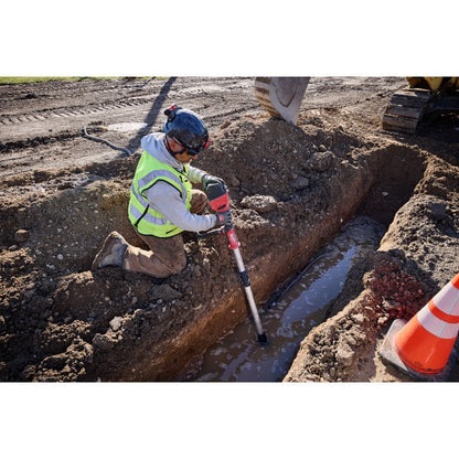 Milwaukee 2940-20 18V Brushless Stick Transfer Pump (Tool Only) showing in use removing water from a trench in the ground