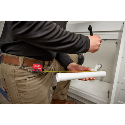 48-22-1706 6ft/2m Keychain Tape Measure showing in use measuring a piece of pipe while attached to a belt loop