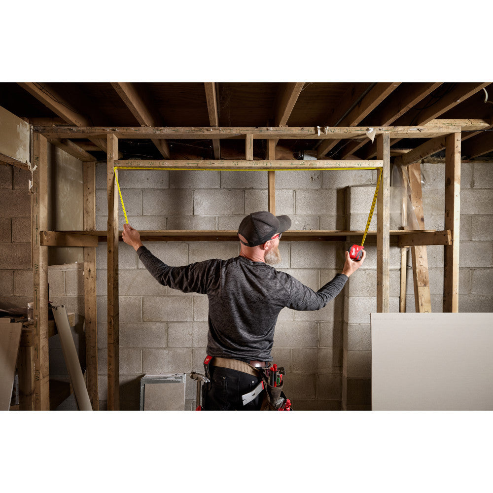 Milwaukee 48-22-1725 25ft Compact Tape Measure showing in use measuring an opening between studs