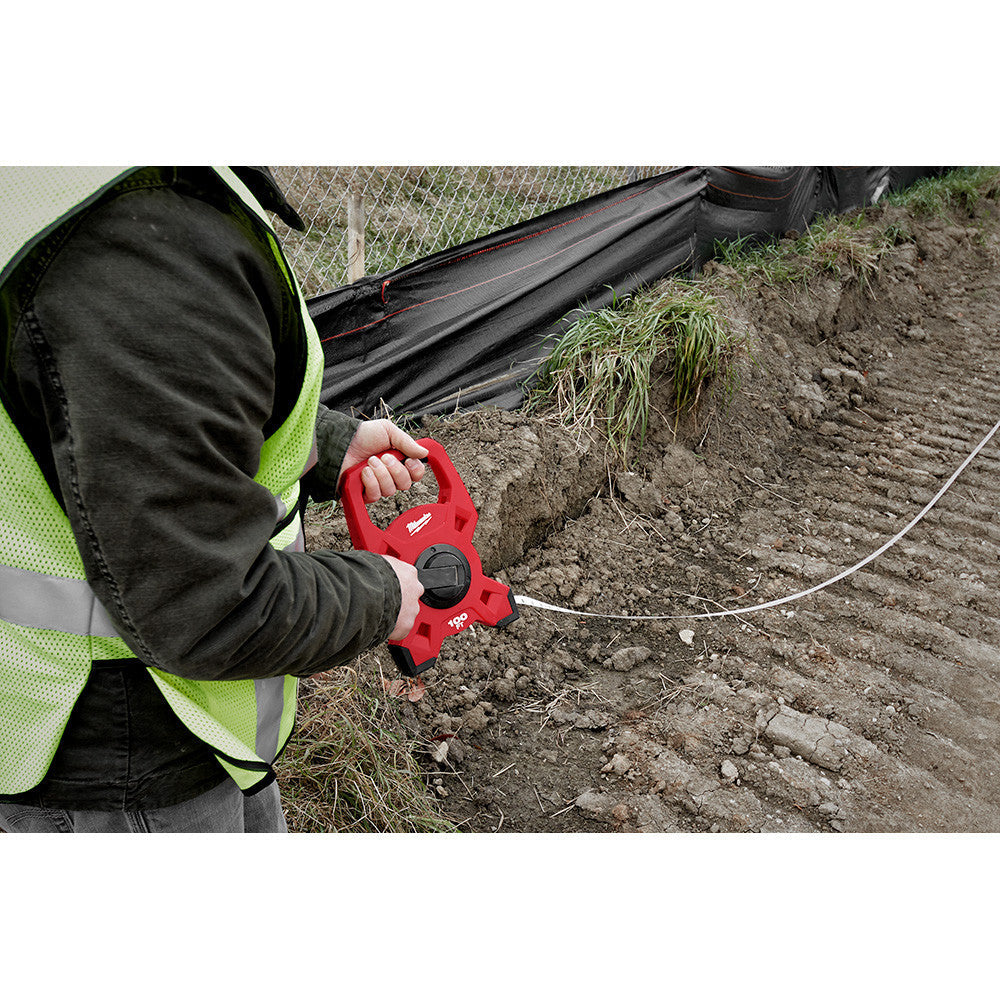 Milwaukee 48-22-5201 100 feet Steel Open Reel Long Tape Measure showing in use measuring long run on a job site
