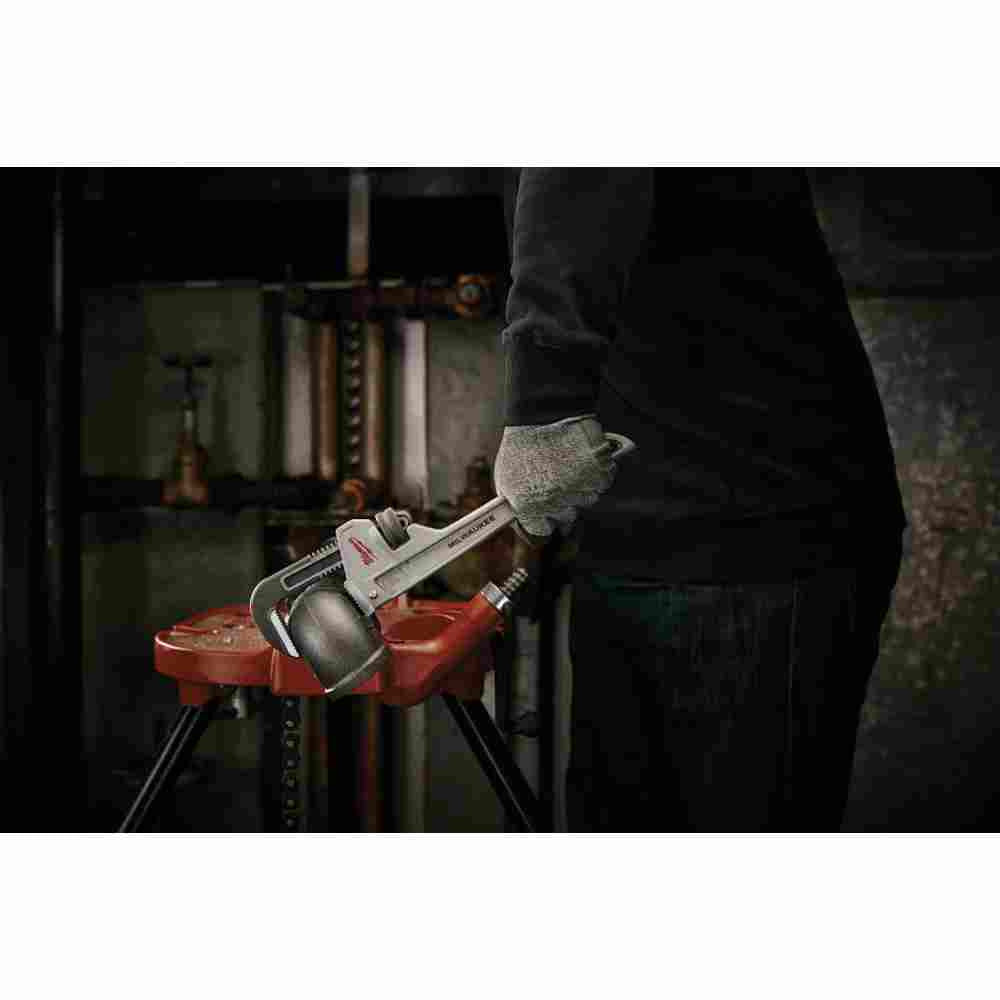 Milwaukee 48-22-7212 12 inch Aluminum Pipe Wrench showing wrench in use tightening an elbow on a length of pipe while strapped to a work bench