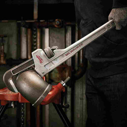 Milwaukee 48-22-7224 24 inch Aluminum Pipe Wrench showing wrench in use tightening an elbow on a length of pipe while strapped to a work bench