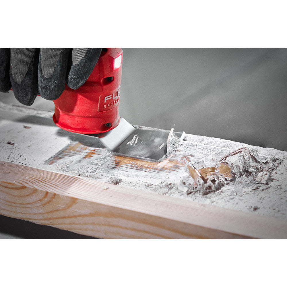 Milwaukee 49-25-2202 OPEN-LOK 2pc 2-inchUniversal Fit Rigid & Flexible Multi-Tool Oscillating Scraper Set showing flexible scraper scraping paint off of a 2X4 dimensional lumber