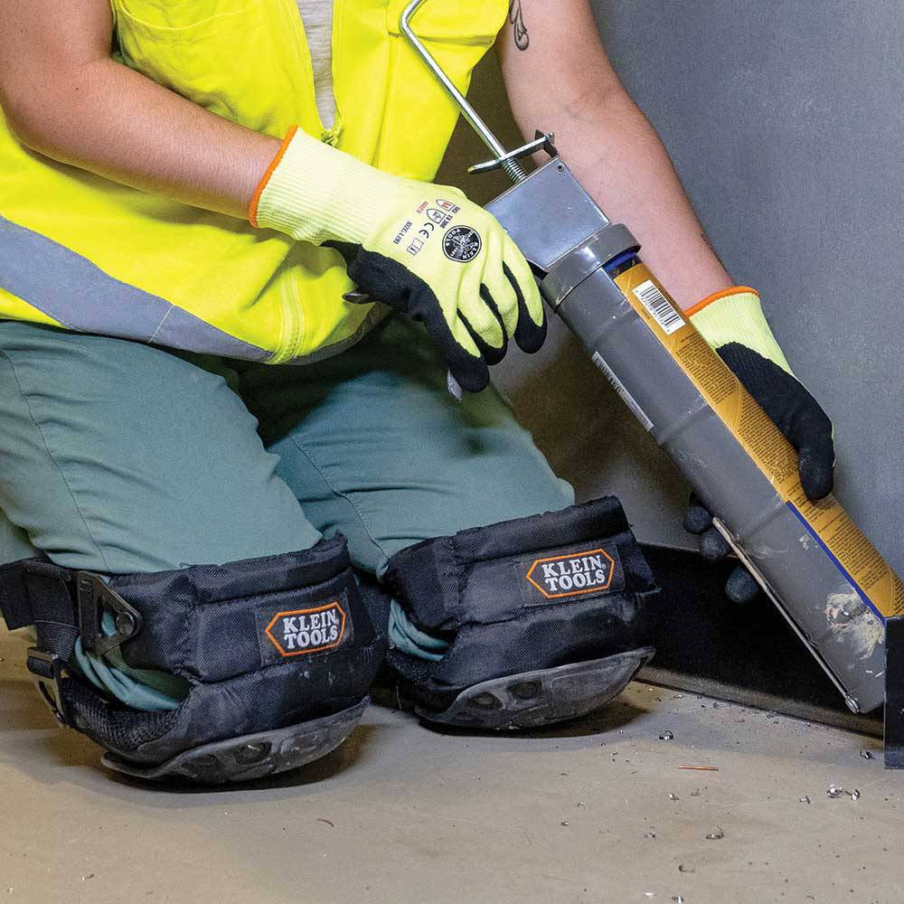 Klein Tools 60344 Hinged Gel Knee Pads showing knee pads being worn while calking at floor level