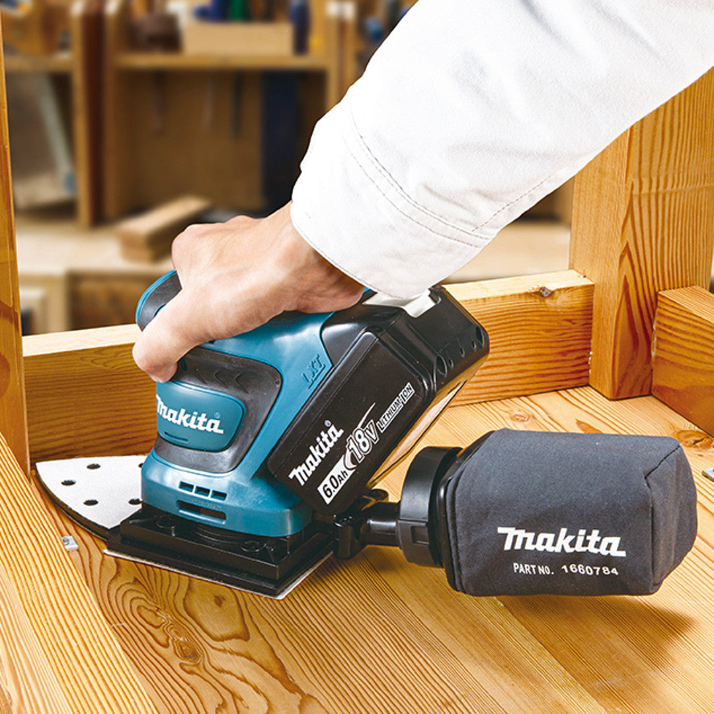 Makita DBO480ZX1 18V LXT Cordless 1/4 Sheet Finishing Sander (Tool Only) showing in use sanding a wood table with included dust bag attached