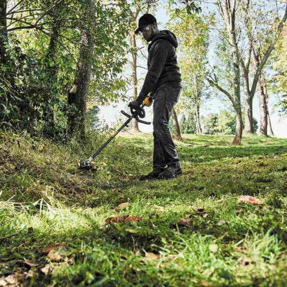 DeWalt DCST972B 60V MAX 17 inch Brushless Dual Line String Trimmer (Tool Only) showing in use cutting cutting tall grasses next to a path
