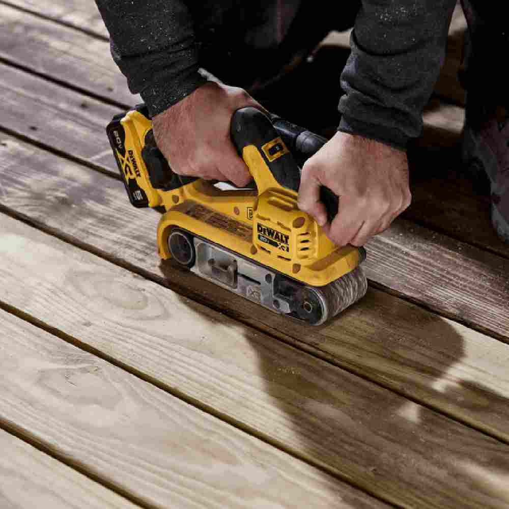 DeWalt DCW220B 20V MAX XR Cordless Brushless 3 inch x 21 inch Belt Sander (Tool Only) showing in use sanding stain off deck boards