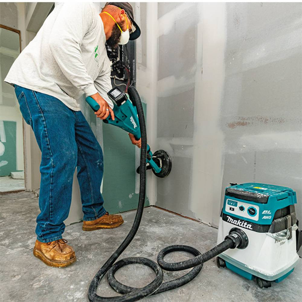 Makita DSL801ZX1 18V Brushless 8-7/8in Drywall Sander (Tool Only) showing in use sanding a wall with a vacuum connected (Battery & vacuum are sold separately)
