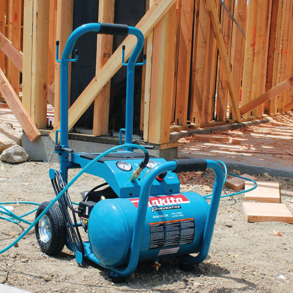 Makita MAC5200 13.8 Amp 3 HP Big Bore 5.2 Gallon Air Compressor showing compressor seating on a jobsite with air line plugged in