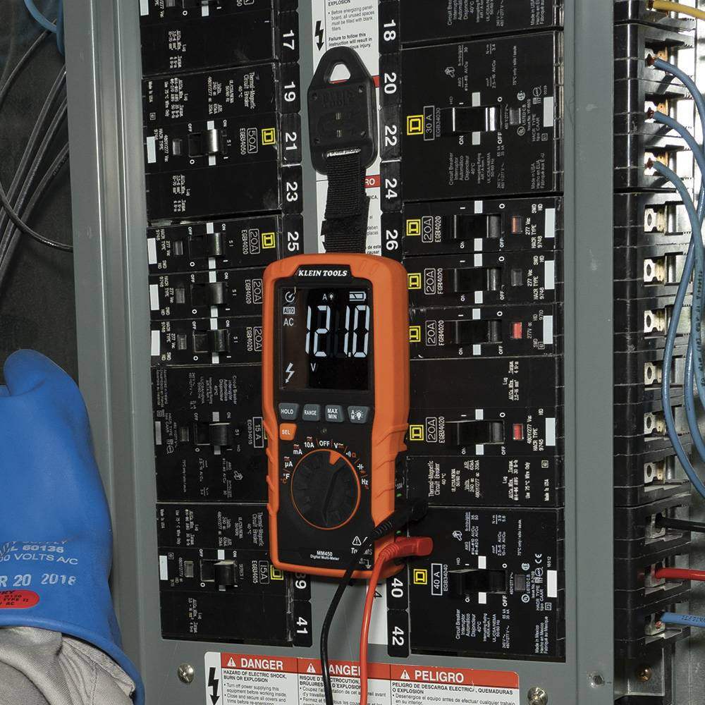 Klein Tools MM450 600V TRMS Auto-Ranging Slim Digital Multimeter showing in use testing voltage with clamp while being mounted to a electrical panel