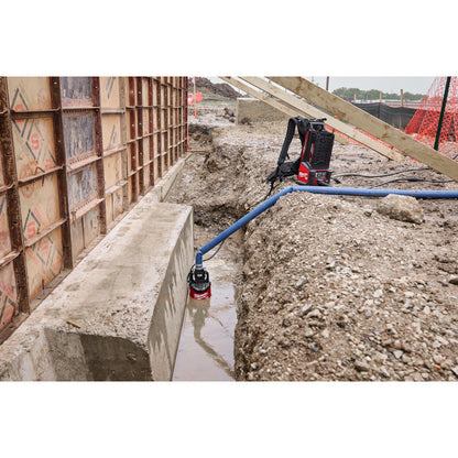 Milwaukee MXF211-1XC MX FUEL 1HP 2in Submersible Pump Kit showing in use pumping water out of a trench along a concrete wall