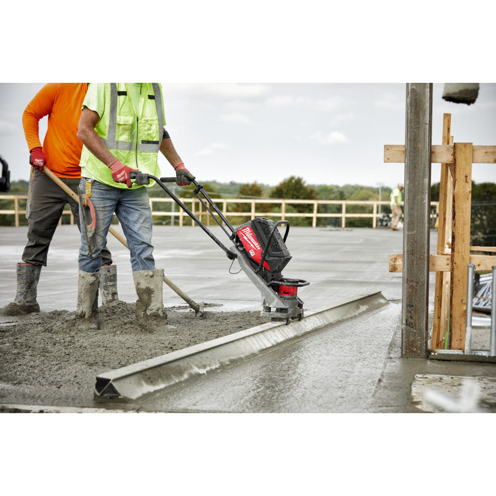 Milwaukee MXF381-2CP MX FUEL Cordless Brushless Vibratory Power Screed Kit showing in use vibrating large slab of poured concrete