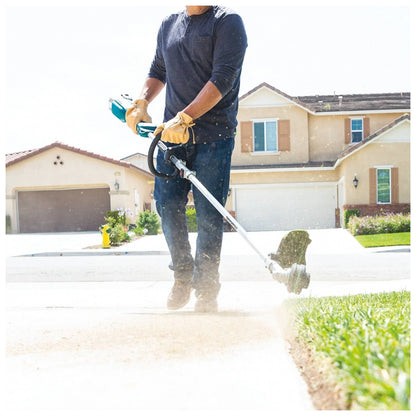 Makita DUX18Z power unit clearing debris from a driveway