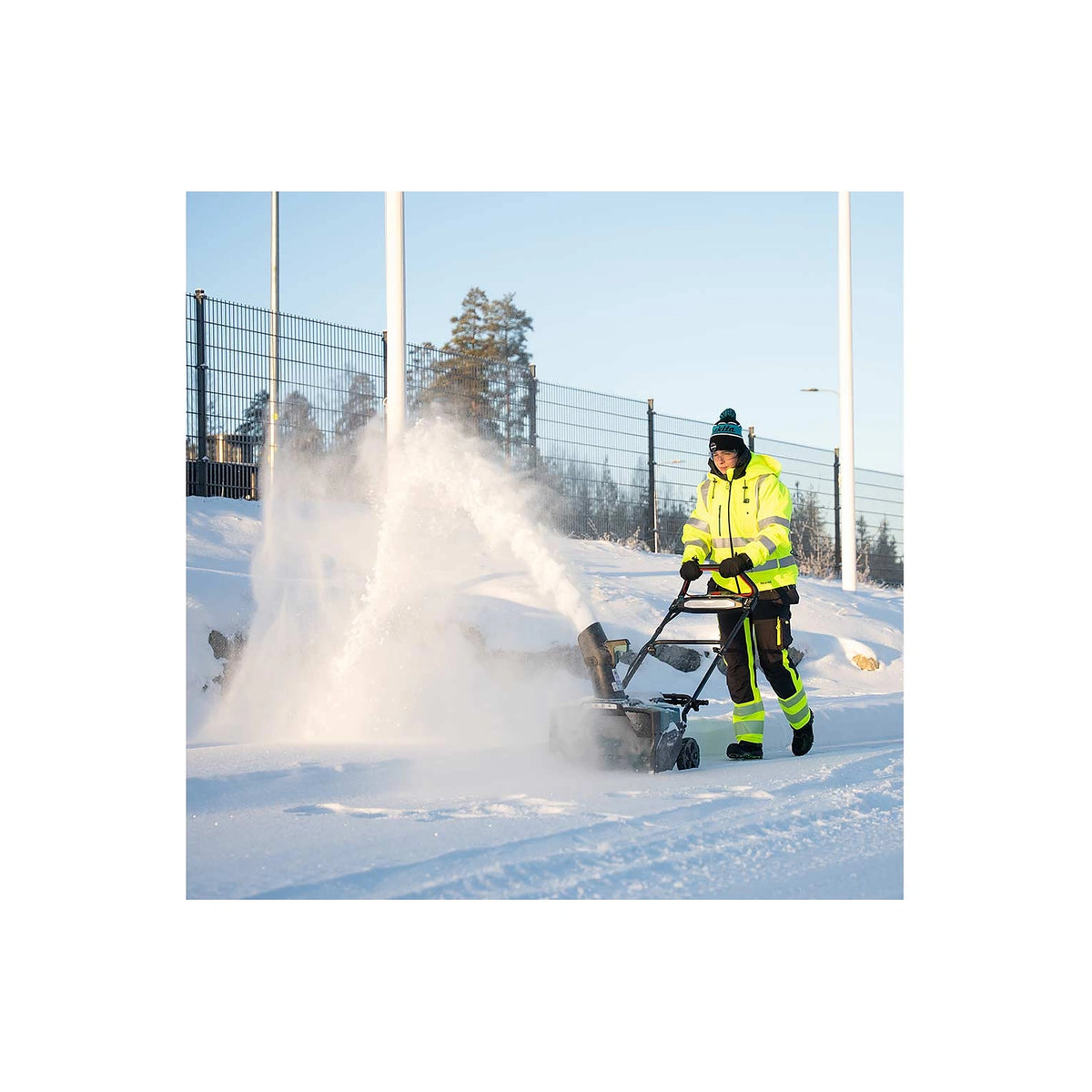 Makita SN001G snow blower throwing snow from a commercial walkway