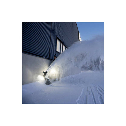 Makita SN001G snow blower throwing deep snow near a building