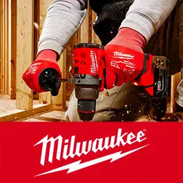 A Milwaukee cordless drill being used by a person wearing red Milwaukee work gloves in a construction setting, with a large Milwaukee logo banner at the bottom