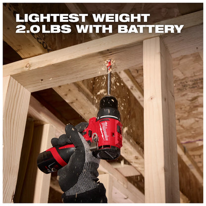 A person wearing gloves uses a red Milwaukee drill to bore a hole through a wooden beam in a construction setting. Sawdust is visible around the drilling spot. The text above reads "LIGHTEST WEIGHT 2.0 LBS WITH BATTERY."