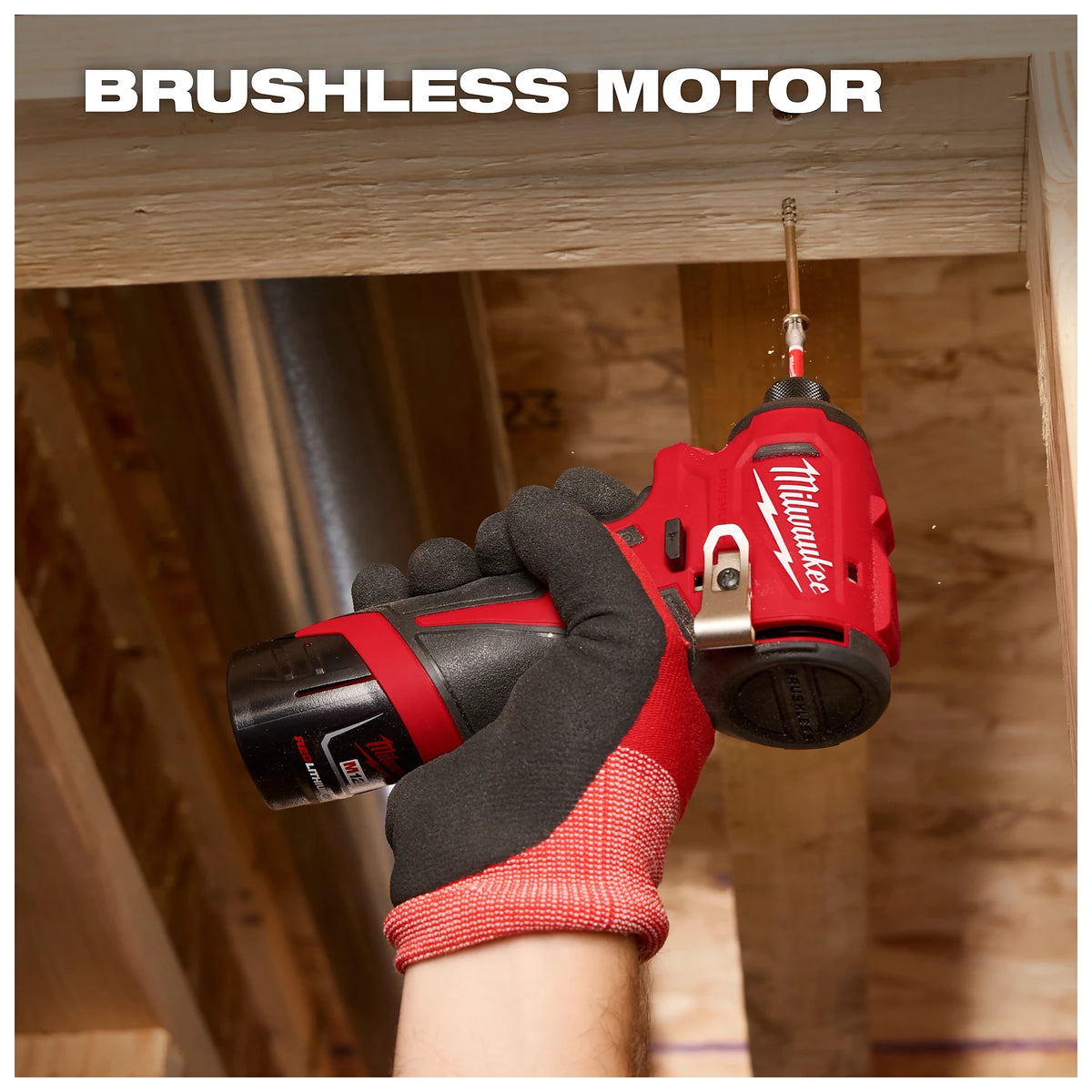 A gloved hand holds a Milwaukee brushless motor drill, screwing a fastener into a wooden beam within a construction area.
