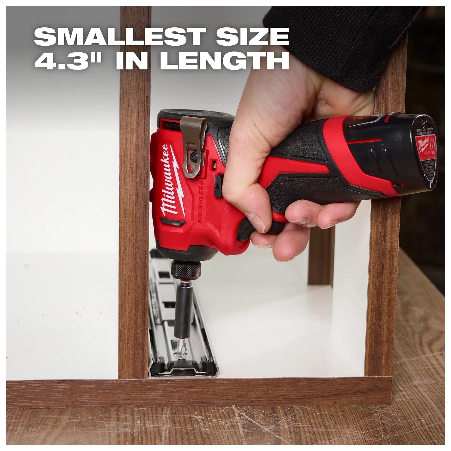 A hand uses a red and black Milwaukee cordless power tool to screw a metal piece onto a wooden frame. The text "SMALLEST SIZE 4.3'' IN LENGTH" is displayed in the upper left corner of the image.
