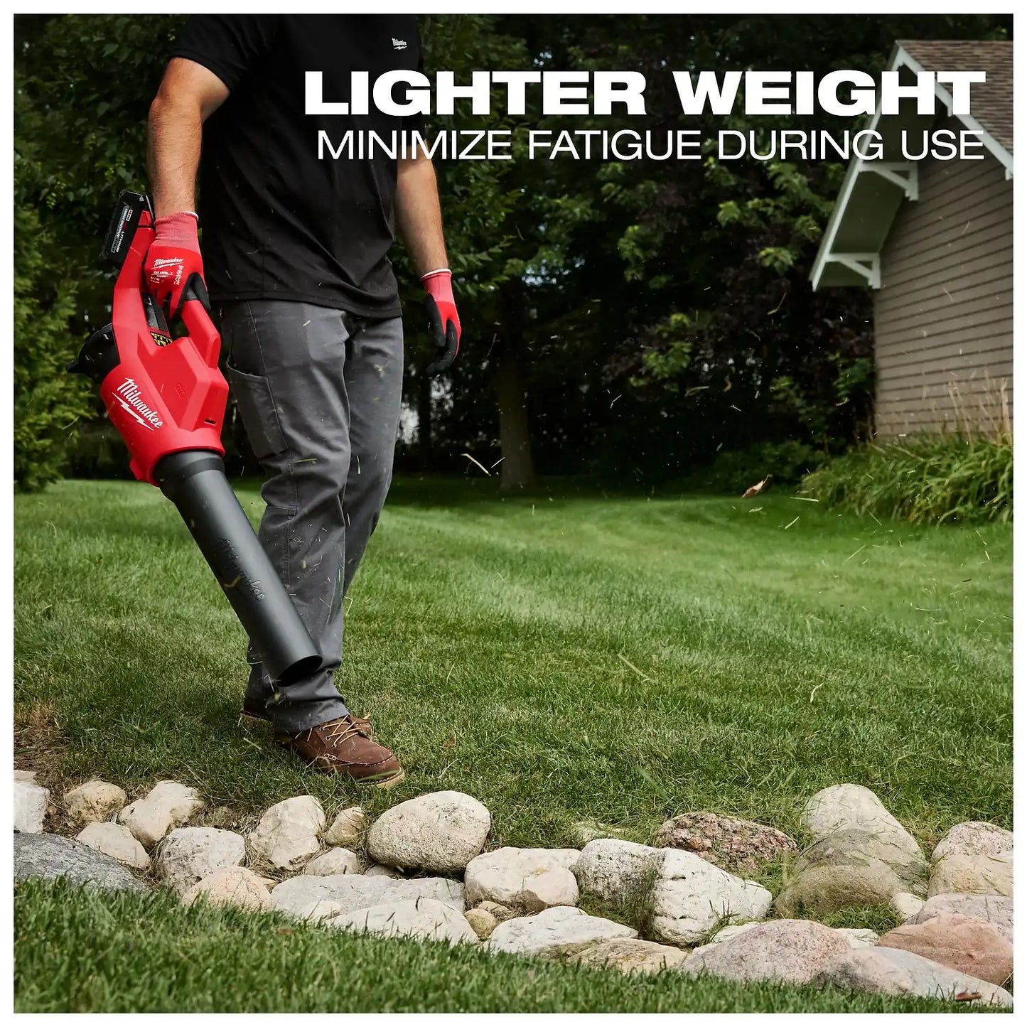 A person uses the Milwaukee M18 Brushless Blower to clear debris from a grassy area bordered by rocks. The text above the person reads, "Lighter weight, minimize fatigue during use."