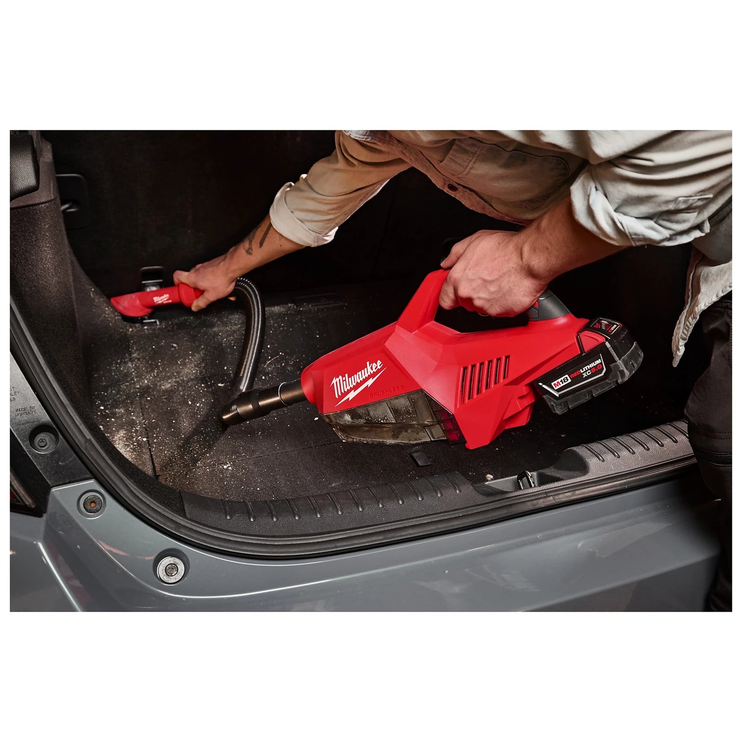 A person uses the M18 Brushless Handheld Vacuum to clean the trunk of a car.