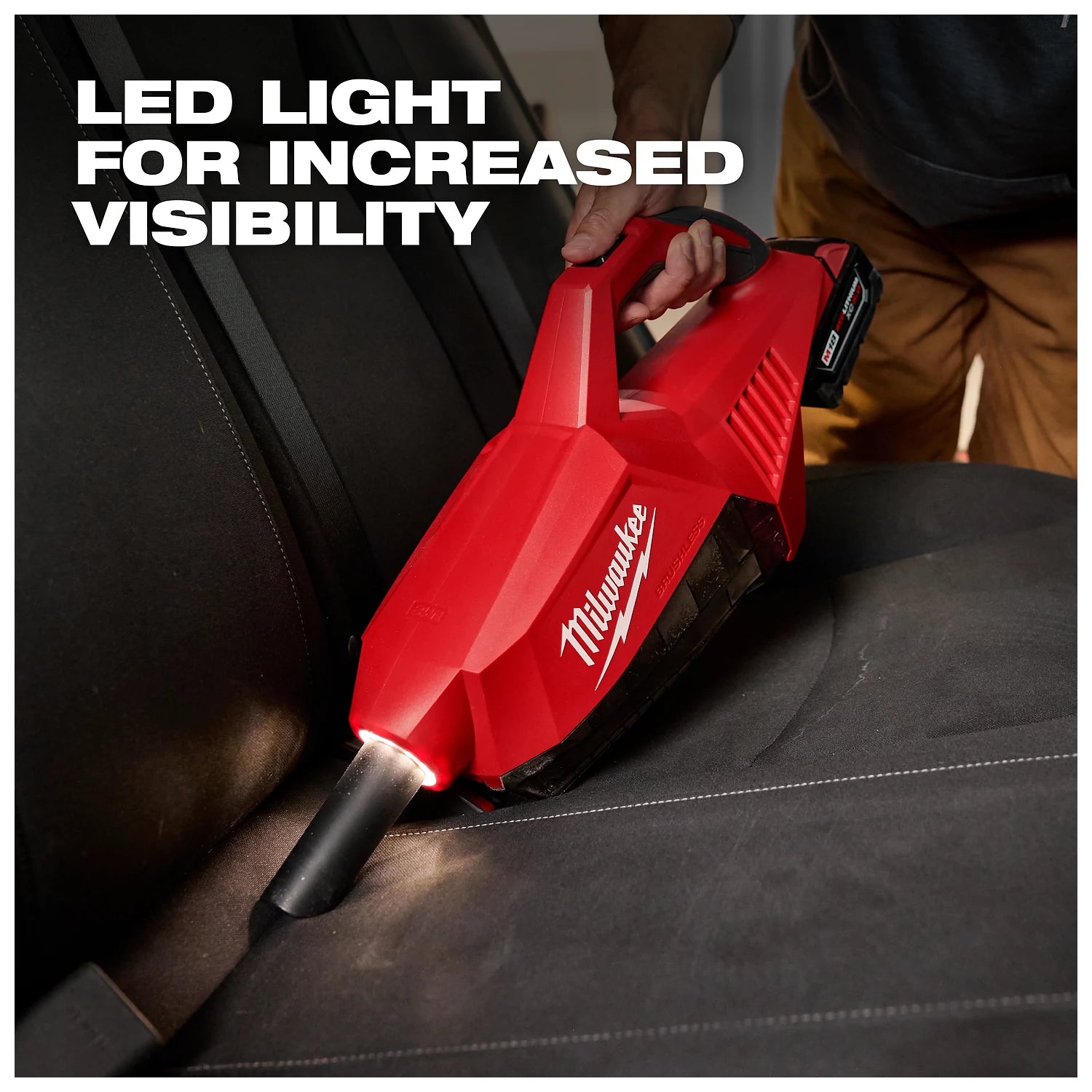 Person using the M18 Brushless Handheld Vacuum with an LED light to clean a car seat, enhancing visibility for thorough cleaning.