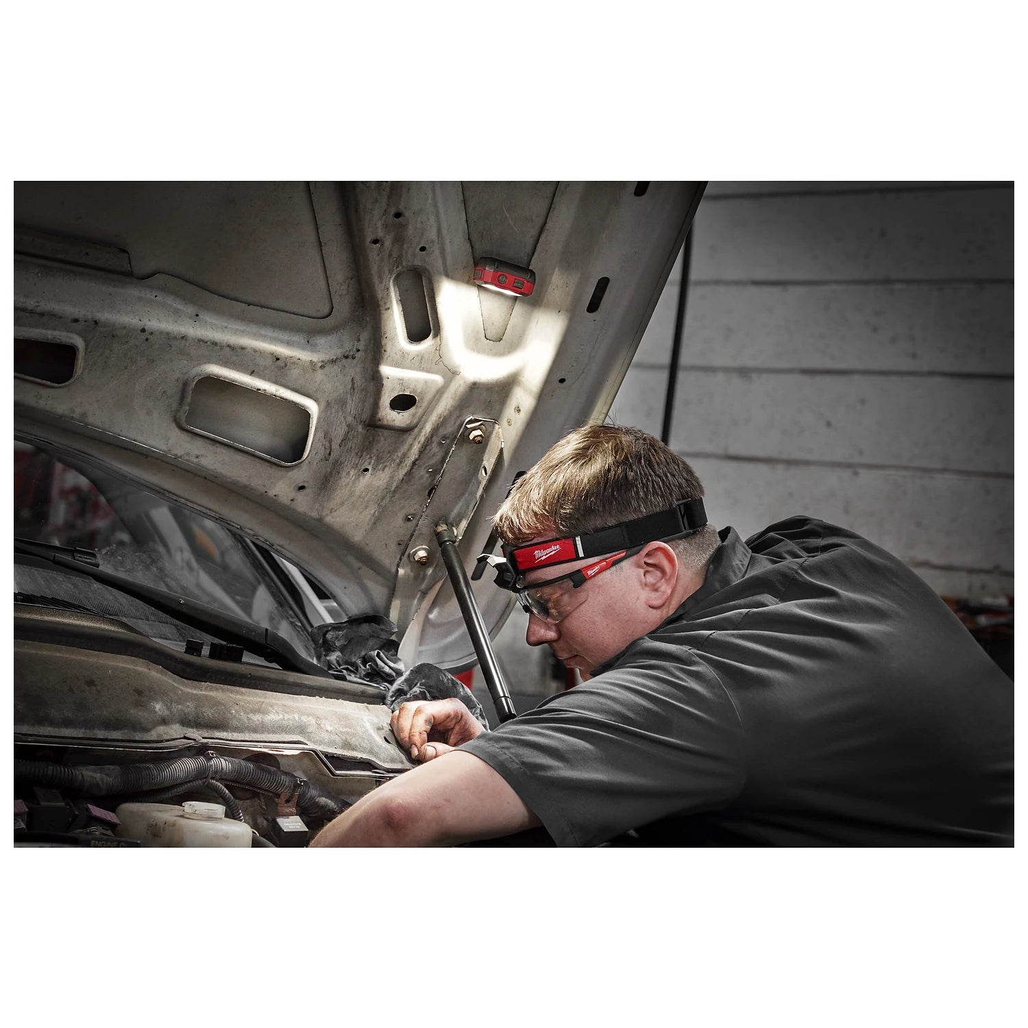 Milwaukee 2012R magnetic task light illuminating an engine bay while the headlamp is worn