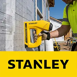 A yellow Stanley cordless nail gun being used by a construction worker on a building exterior, with a large yellow banner at the bottom reading STANLEY